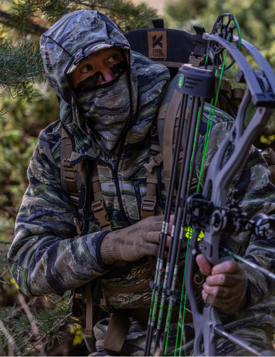 Person in camouflage gear holding a crossbow in a forest setting